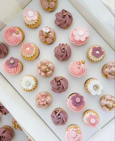 there are many cupcakes in the box on the table and one is decorated with flowers