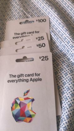 two apple gift cards sitting on top of a bed