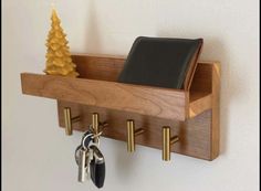 a wooden shelf with keys, wallet and other items hanging on the wall next to a small christmas tree