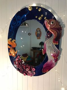 a mirror that is on the side of a wall with lights around it and an image of a fish