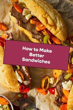 two sandwiches sitting on top of wax paper next to bowls of vegetables and sauces