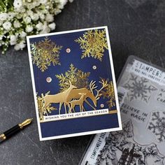 a close up of a card on a table next to some flowers and a pen