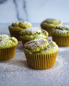 several green muffins with powdered sugar on them sitting on a counter top