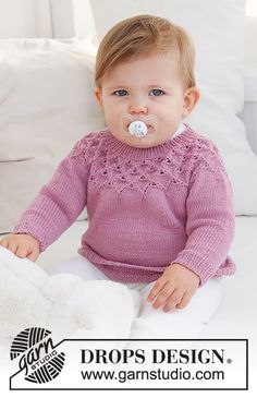 a baby wearing a pacifier sitting on a bed