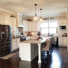 a large kitchen with white cabinets and black refrigerator freezer next to a stove top oven