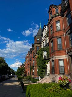 a row of red brick buildings on a sunny day with blue skies and clouds in the background