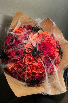 a bouquet of red roses wrapped in spider web