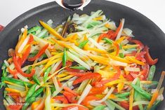 stir fry vegetables being cooked in a wok on top of the stove with tongs