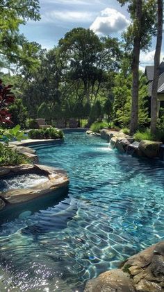 an outdoor swimming pool with rocks and water features, surrounded by lush greenery on both sides