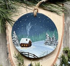 a wooden ornament with a cabin in the woods on it's side