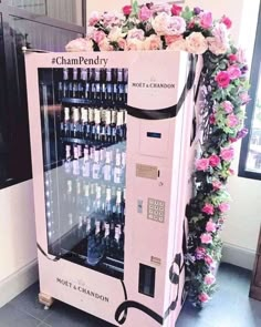 a pink champagne vending machine with roses around it