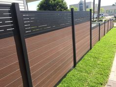 a wooden fence with black slats on the sides and green grass in front of it