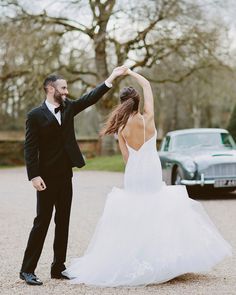 a bride and groom dancing in front of an old car