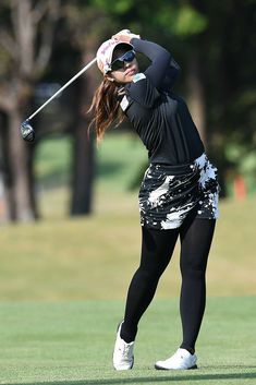 a woman swinging her golf club on the course