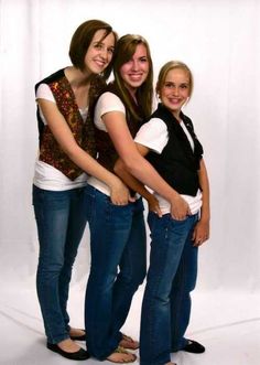 three young women are posing for a photo together in front of a white background, with their arms around each other