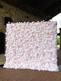 a large pink and white flowered wall in front of a brick building