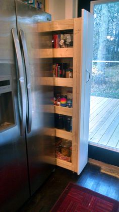 a stainless steel refrigerator freezer sitting next to a wooden shelf filled with spices and condiments