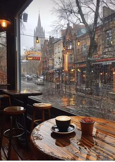 a rainy day in the city with some tables and chairs on the sidewalk, looking out at an outside cafe