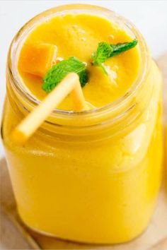 a glass jar filled with yellow liquid and garnished with mint