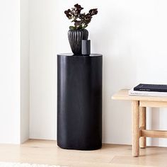 a black planter sitting on top of a wooden table next to a white wall