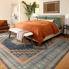 a large bed sitting on top of a wooden floor next to a chair and table