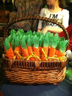 a basket filled with carrots sitting on top of a table next to a woman