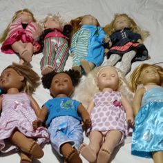 a group of dolls laying on top of a bed