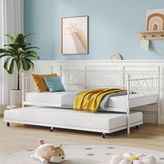 a white daybed sitting on top of a wooden floor next to a potted plant