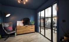 a living room with blue walls and wooden furniture in front of a large sliding glass door