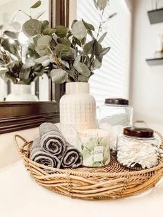 a basket filled with towels and candles sitting on top of a bathroom counter next to a mirror