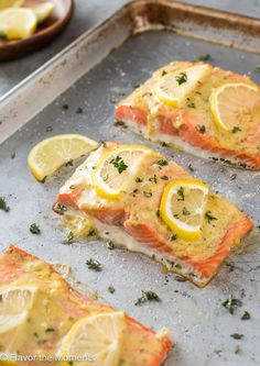 salmon with lemons and herbs on a baking sheet