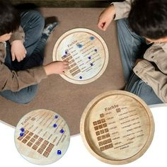 two young boys sitting on the floor playing with wooden coasters that spell out numbers