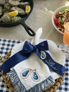 a blue and white table cloth on a basket next to some plates with oysters