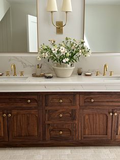 a bathroom vanity with two sinks and a large mirror above it, along with flowers in a bowl on the counter