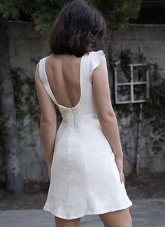 the back of a woman's white dress is seen in this image, as she stands on her skateboard