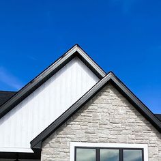 a black and white cat sitting on the window sill of a brick house with a blue sky in the background