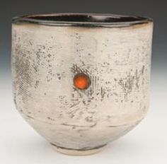 a white and brown bowl with an orange dot in the center on a gray background