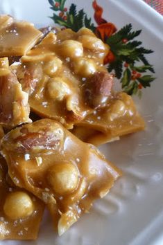 a white plate topped with pasta and meat covered in gravy next to a sprig of holly