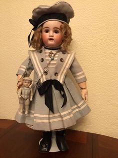 a doll is standing on a table with a hat and coat over it's head