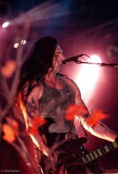 a woman with long hair standing in front of a microphone on stage at a concert