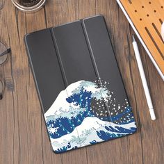 an ipad case with the great wave on it, sitting next to some coffee and glasses