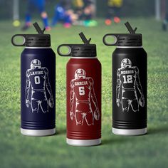 three sports water bottles sitting on top of a field