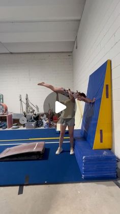 a man standing on top of a blue and yellow trampoline in a gym