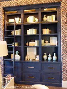 a blue bookcase with many books and vases on it in a living room