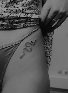 a woman's stomach with a snake tattoo on the side and her right leg