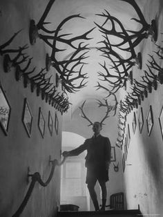 a black and white photo of a man with antlers on his head in the hallway