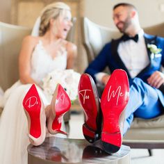 a bride and groom sitting in chairs with red shoes