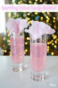 two glasses filled with pink liquid sitting on top of a table next to a christmas tree