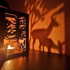 the shadow of a deer on a wall next to a candle