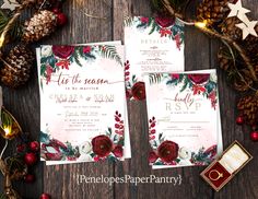 the wedding stationery is decorated with red flowers and greenery, including pine cones